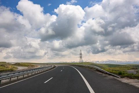 Open highway stretches forward through flat landscape under bright clouds Stock Photos