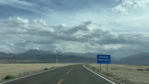 An open highway sweeps across a vast arid plateau toward a dramatic, Stock Footage 342577253