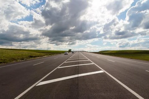 Open Highway Through Green Fields Under Dramatic Cloudy Sky Stock Photos