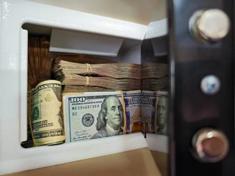 Open home safe full of hundred-dollar bill stacks and cash savings. Stock Photos