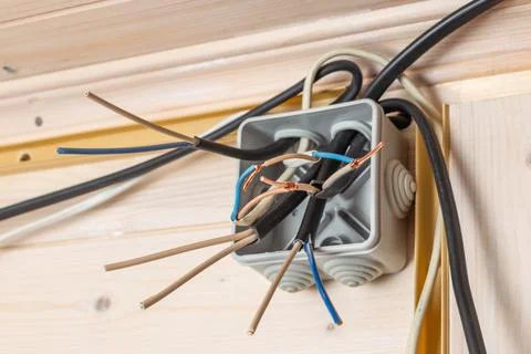 Open junction box with multiple exposed copper, blue, and brown wires ready f Stock Photos