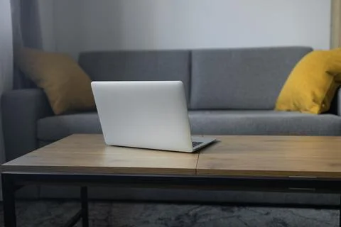 Open laptop on coffee table in modern living room interior without people Stock Photos