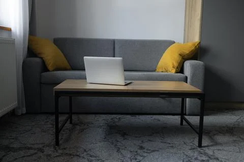 Open laptop on coffee table in modern living room interior without people Stock Photos