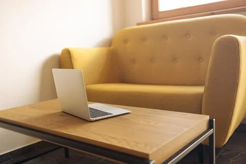 Open laptop on coffee table in modern living room interior without people Stock Photos