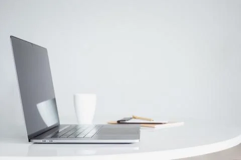 Open laptop computer with coffee and notebook on white table. Stock Photos