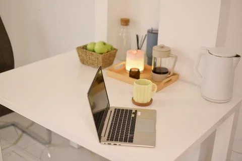 Open laptop computer on white desk with coffee press apples diffuser kettle Foto stock