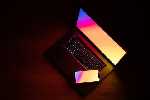 Open laptop with digital tablet and smartphone. Dark with colorfull technolog Stock Photos