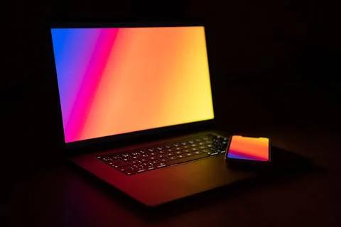 Open laptop with digital tablet and smartphone. Dark with colorfull technolog Stock Photos