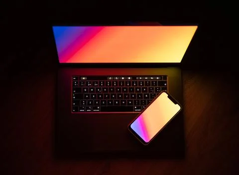 Open laptop with digital tablet and smartphone. Dark with colorfull technolog Stock Photos