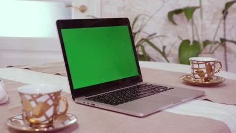 Open laptop with green chromakey screen and cups of tea Stock Footage 229721962