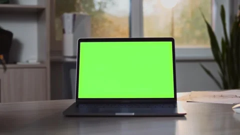 An open laptop with green screen sits on a desk in a modern bright sunny office Stock Footage 307598706
