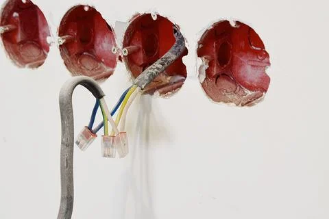 An open light switch with electrical wires hanging from the wall. Stock Photos