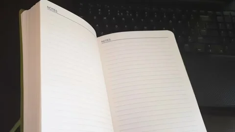 Open Lined Notebook on Laptop with Pages Moving in Gentle Airflow Stock Footage 336310935