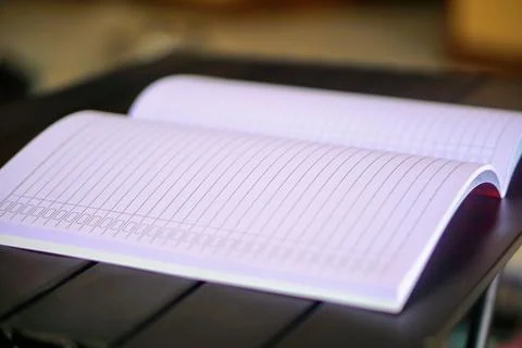 An open lined notebook on a table with soft lighting, representing the concepts Stock Photos