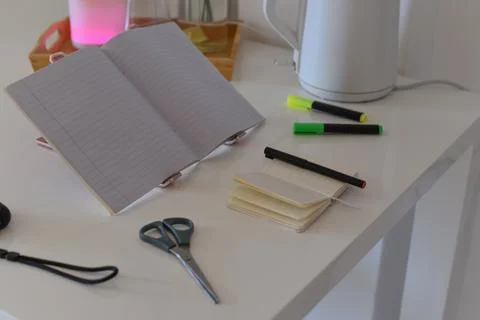 Open lined notebook with workspace items on white table elevated view Foto stock
