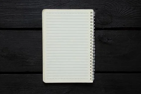 Open lined spiral notebook lies on black wooden background and top view, temp Stock Photos