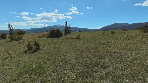Open meadow stretches under clear blue sky. Balkan, Eastern Europe, POV Video stock 333442620