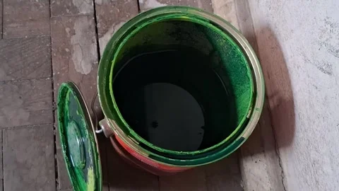 Open metal can filled with dark green liquid paint Stock Footage 346727936