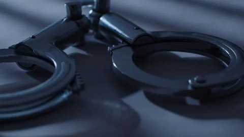 Open Metal Handcuffs Resting on Dark Surface, Close-up Shot Vídeos de archivo 337405896