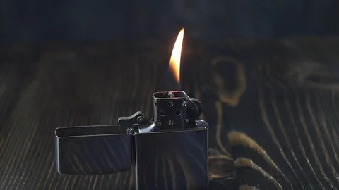 Open metal lighter  with flame on dark background Stock Footage 118585564