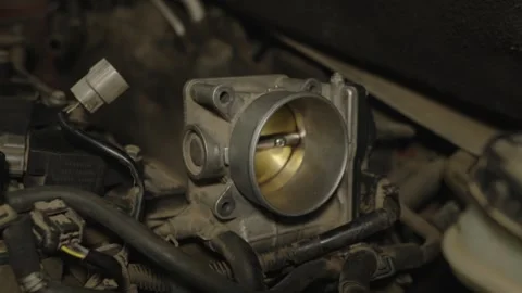 An open metallic car throttle body valve installed in a dusty engine bay. Stock Footage 340558753