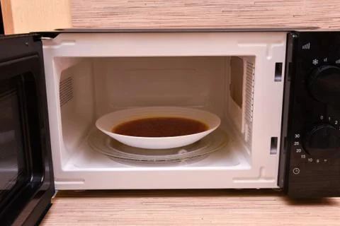 Open microwave with soup inside. Image of the microwave oven. Modern microwav Stock Photos