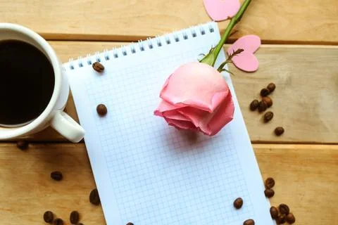 Open mockup notebook, coffee cup and pink rose on wooden background. Beautifu Stock Photos