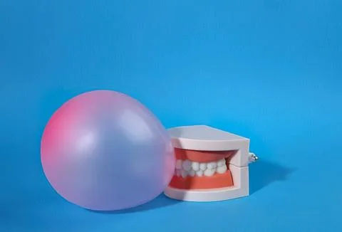 Open mouth with teeth next to a large shiny ball on blue background Stock Photos
