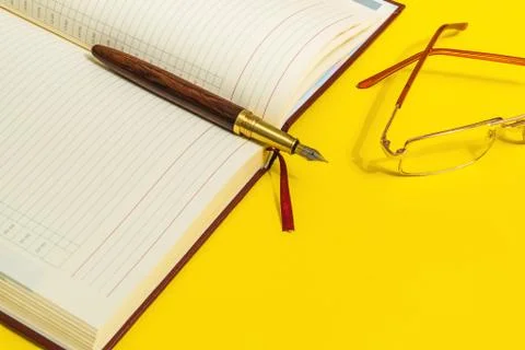 Open note book with pen and glasses on the office desk Stock Photos