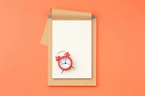 Open notebook and alarm clock on orange background Stock Photos