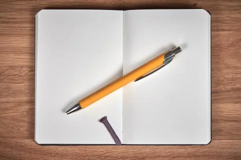 Open notebook and ballpoint on a brown wooden table Stock Photos