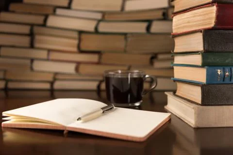 Open notebook and cup on the background of books Stock Photos