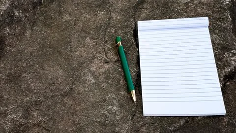 Open notebook and green pen on natural stone surface Stock Photos