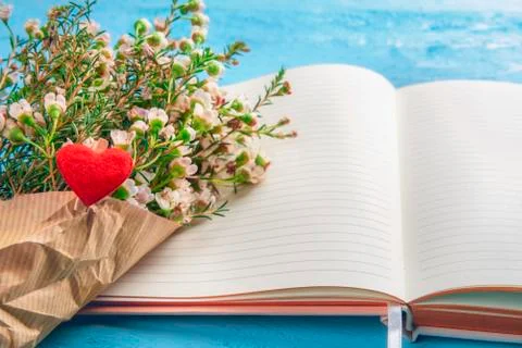 Open notebook and white flower bouquet with a red heart Stock Photos
