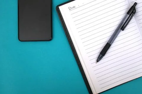 An open notebook with a ballpoint pen on it and a smartphone next to it on .. Stock Photos