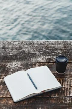 Open notebook with blank grid pages and pen on rustic wooden table beside t.. Stock Photos