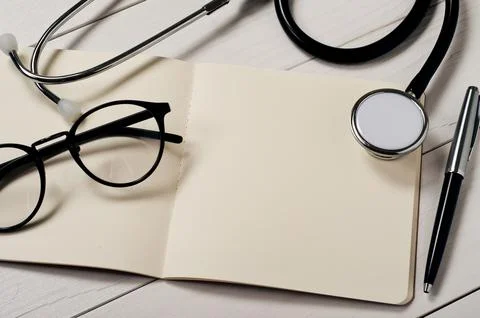 Open notebook with blank pages with stethoscope, glasses and pen on a white.. Stock Photos