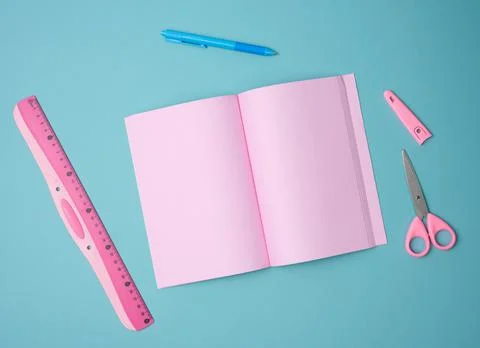 Open notebook with blank pink sheets, scissors and ruler on blue background,  Stock Photos