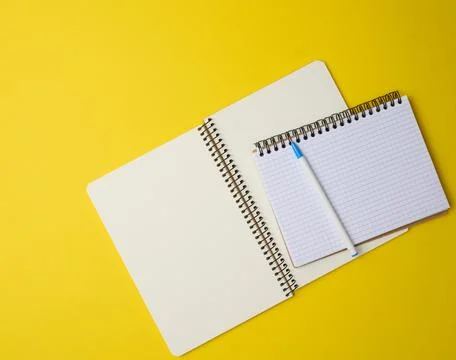 Open notebook in a cage with white blank sheet and on a yellow background, to Stock Photos