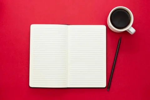 Open notebook with coffee cup on red background. Foto stock