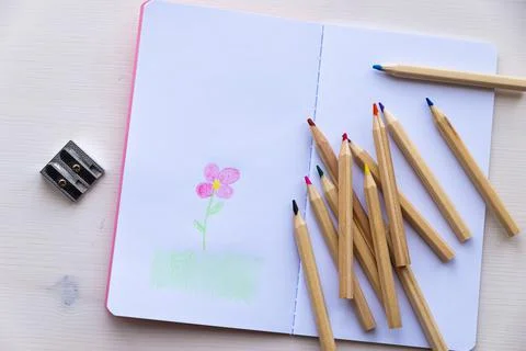 Open notebook, with colored crayons and drawing Stock Photos