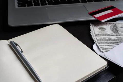 An open notebook with credit card, pen, dollars and laptop Stock Photos