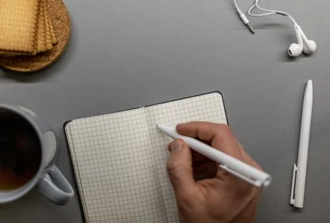 Open notebook cup cookie and pens on grey table Stock Photos