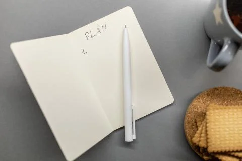Open notebook cup cookie and pen on grey table Stock Photos