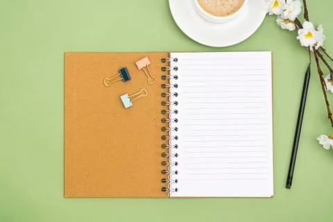 Open notebook with empty page and coffee cup. Table top, work space on green  Stock Photos
