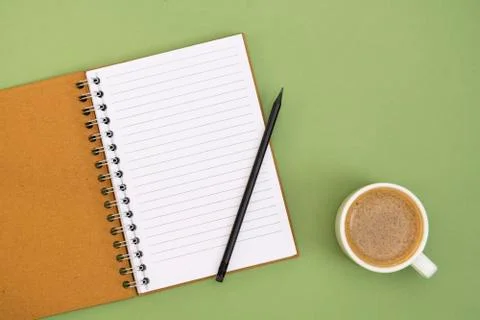Open notebook with empty page and coffee cup. Table top, work space on green  Stock Photos