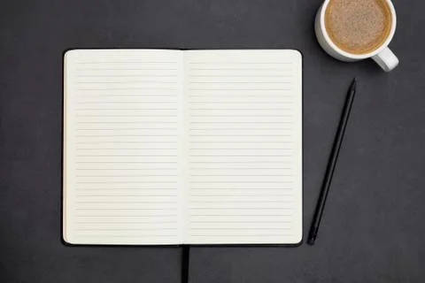Open notebook with empty page and coffee cup. Table top, work space on dark b Stock-Fotos