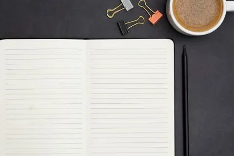 Open notebook with empty page and coffee cup. Table top, work space on dark b Stock-Fotos