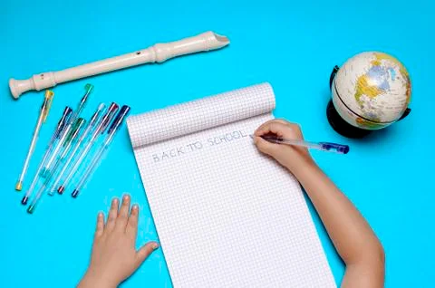 Open notebook with flute, globe and hands of Caucasian girl. Foto stock