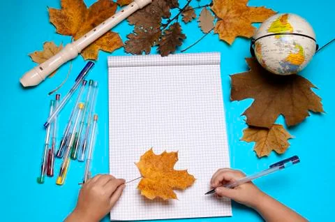 Open notebook, flute, globe, autumn leaves and hands of Caucasian girl Foto stock